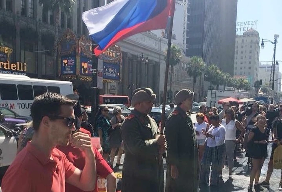Пара мужиков с российским флагом и в странных шинелях и шапках (такой советскую форму показывали в американских фильмах) «взяли под охрану» разбитую звезду Дональда Трампа. Фото: twitter.com/adamcbest