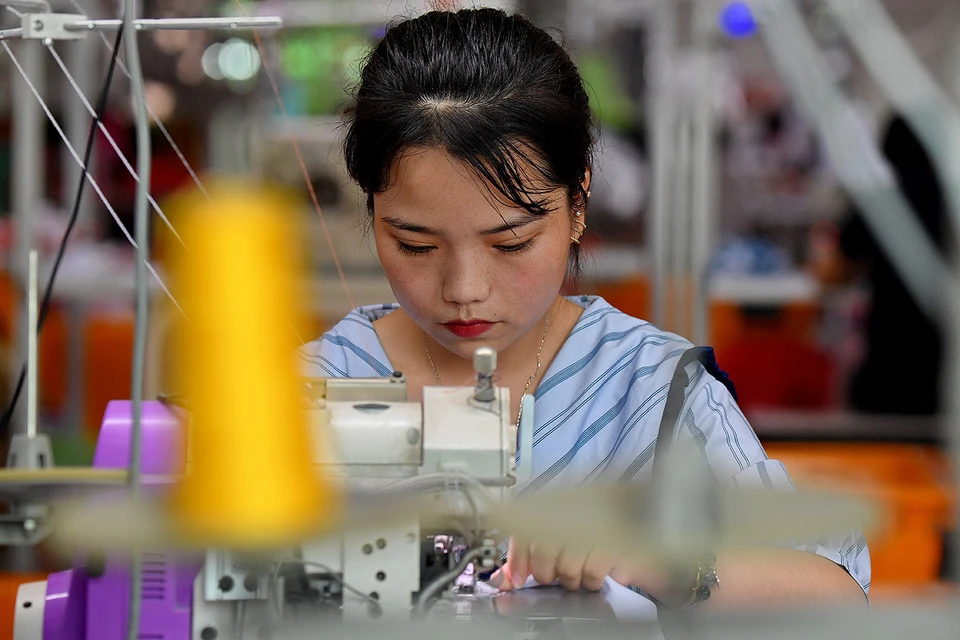 Работница китайской фабрики по производству одежды на смене.