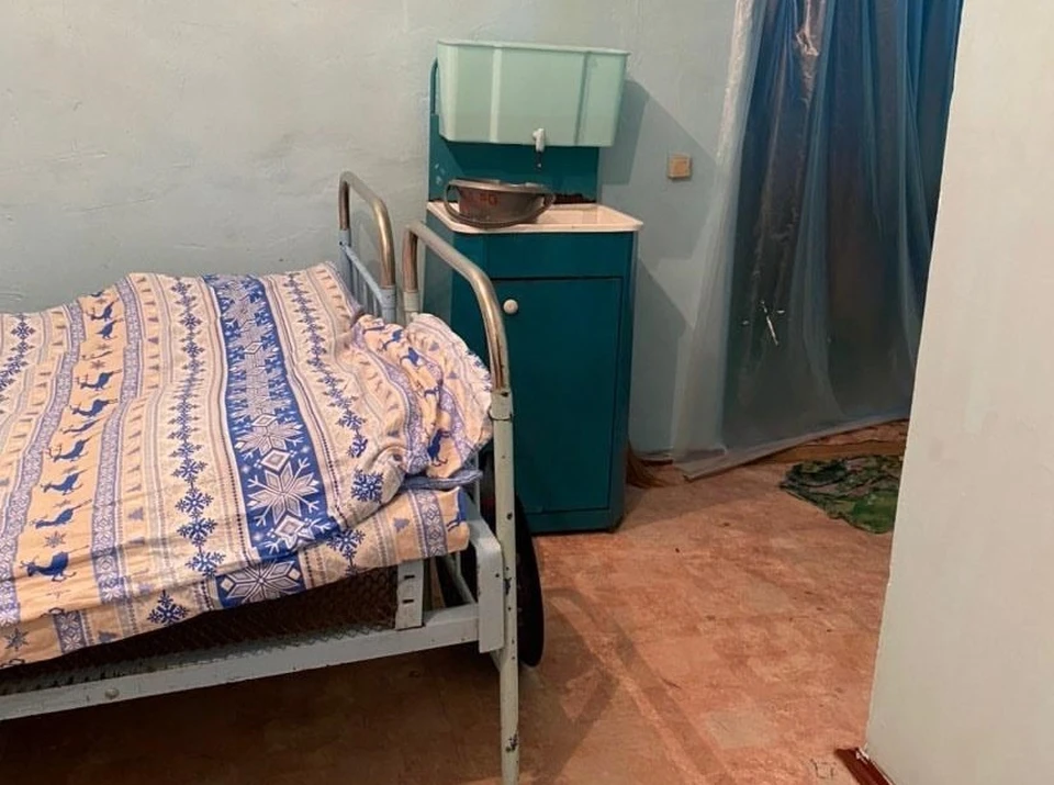 В палате стоит уличный рукомойник, на окнах и двери вместо штор висит пленка, лампочки на потолке без светильников, а линолеум в углу ободран