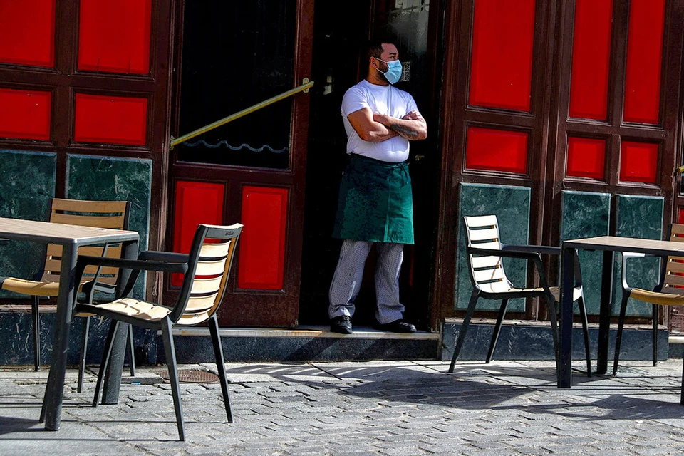 Официант ждёт гостей на пороге одного из кафе в Мадриде.
