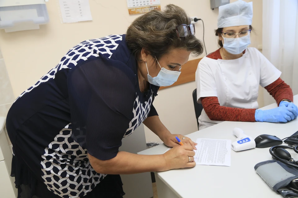 Женщина подписывает согласие на прививку вакцины для профилактики коронавирусной инфекции.
