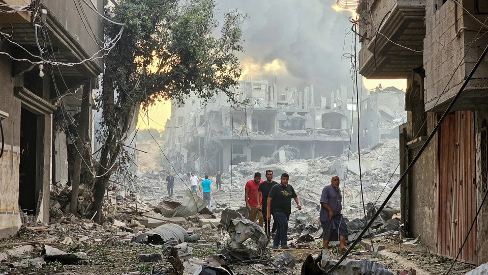 Палестинцы у развалин здания, разрушенного израильским обстрелом, север сектора Газа.