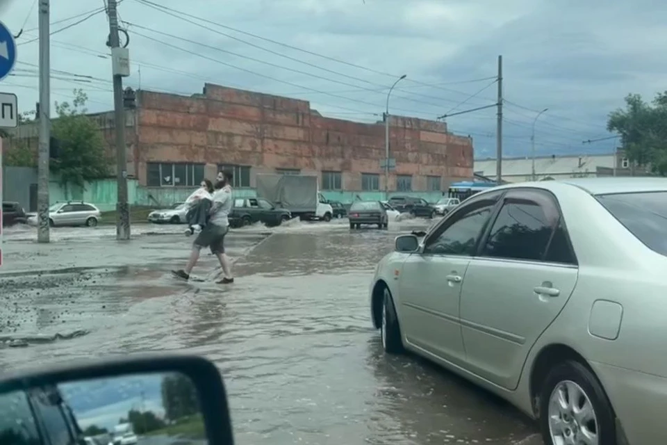 В Новосибирске пешеходы несли детей на руках через затопленную дорогу. Фото: Елена Шепелева