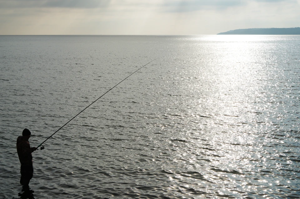 Рыбак ловит рыбу на Песчаном пляже Мариуполя