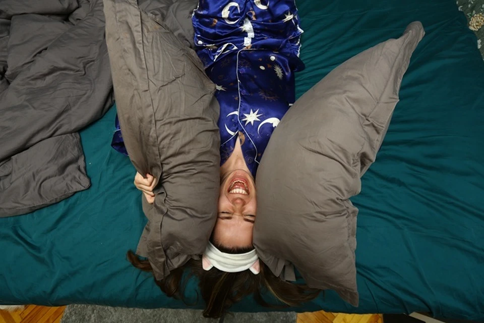 Девушка закрывает уши подушками и кричит