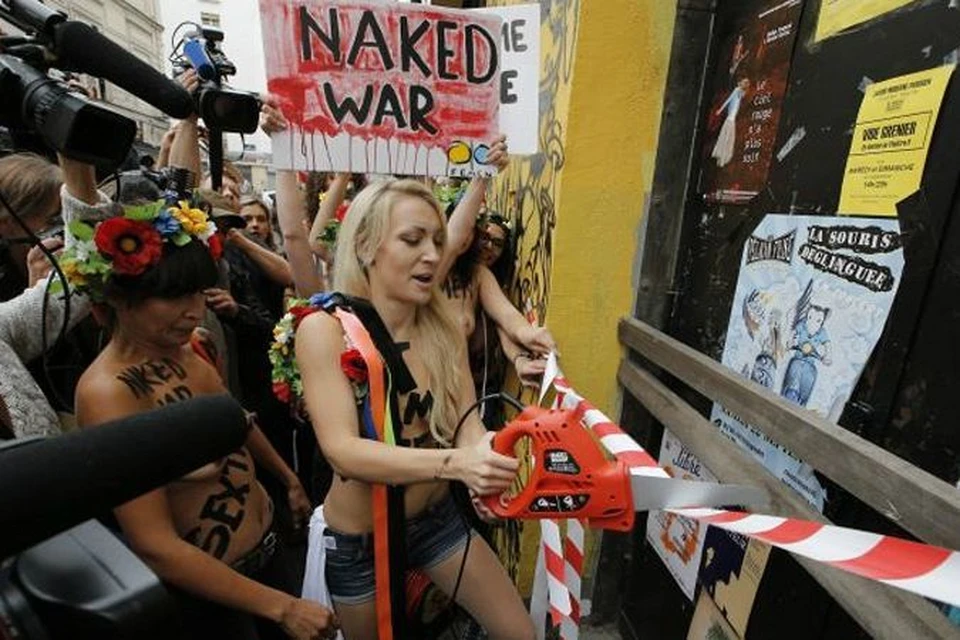 Лидер Femen Инна Шевченко в окружении товарок «открывает» новый парижский офис группы с помощью бензопилы, которой спиливала православные кресты.