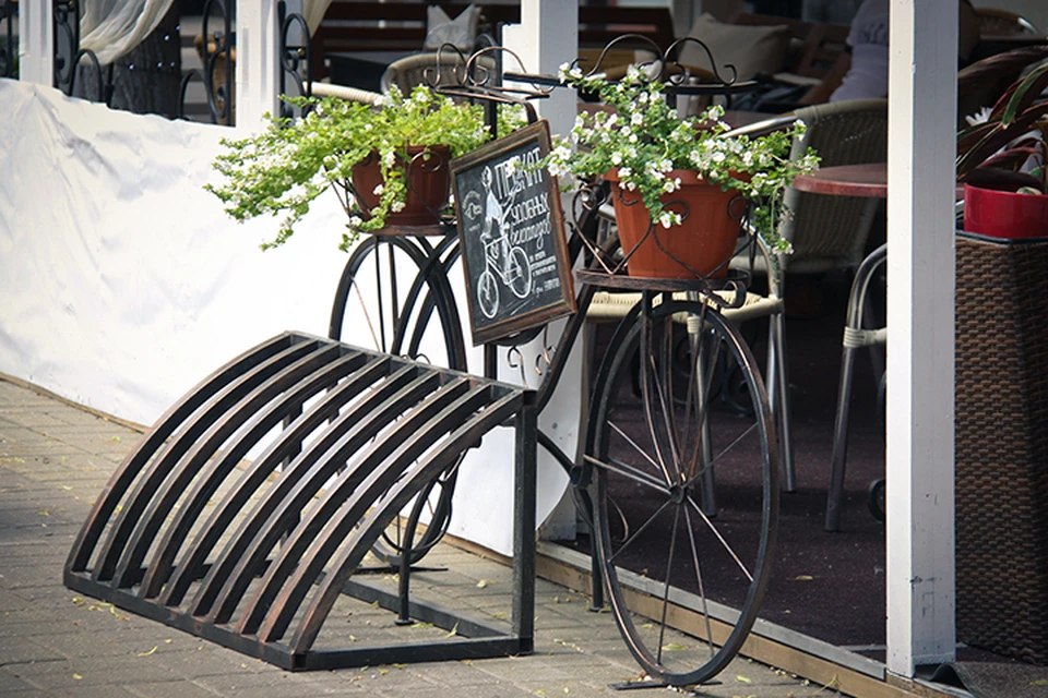 Рядом с летней верандой кофейни «Гаврош» установили велопарковку, которую украшает велосипед-клумба.