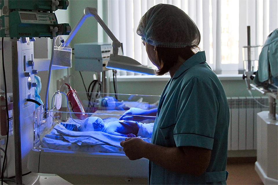 Медсестра проверяет состояние младенца в отделении детской реанимации роддома.