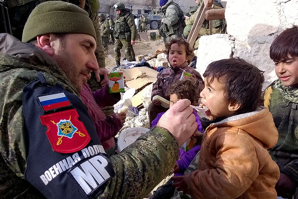 Боец российской военной полиции кормит сирийских детей в районе Аль Миасар в восточной части Алеппо. ФОТО Тимур Абдуллаев/NewsTeam/ТАСС